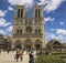 A group of people standing in front of Notre Dame de Paris in the background