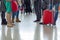 Group of people are standing with suitcases and bags standing in the airport hall.