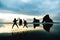 A group of people taking a photo with with famous rocks. Sunset scene golden light and silhouette. Wharariki Beach Nelson, South