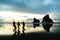 A group of people taking a photo with with famous rocks. Sunset scene golden light and silhouette. Wharariki Beach Nelson, South