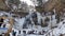 Group of people visit frozen waterfall in winter