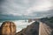 Group of people walking on a boardwalk near the sea with a lot of rock formations