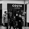 Group Of People Walking PAst A Branch Of High Street Coffee Shop Costa Wearing Face Coverings