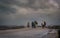 A group of people walking and trying to keep umbrellas in a windy day and lightning in background