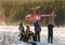 Group of people watches a commercial helicopter with the Michelin logo landing on the snowy field.