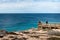 Group of people watching whales migration from an observation platform at the shore. Whale close to the cliff. Nature observation