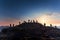 A group of people working on top of a house roof and placing tiles. Sunset backlight. People silhouettes