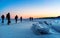 Group of photographer travellers walking on frozen lake Baikal, Russia. Hunting sunrise in winter