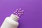 Group pink tablets. Capsules spilling out of white bottle. Viole