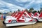 Group of plastic pleasure catamarans with slides of red and white color stand on an empty sandy beach in a seaside resort on