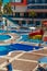 A group of plump women sitting on the edge of the pool and talking. Women are dressed in bathing suits. Tourists have a rest at