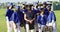 Group portrait of diverse team of female baseball players and coach in face masks on sunny pitch