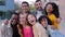 Group portrait of diverse young happy people smiling at camera at city street