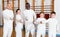 Group portrait of young fencers with coaches holding rapiers in training room