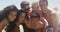 Group portrait of young interracial friends huddled enjoying the beach