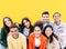 Group portrait of young multiethnic student friends against yellow wall