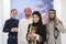 Group portrait of young Muslim people women in fashionable hijab dress with three Arabian men using smartphones at