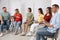 Group of pregnant women with men and doctor at courses for expectant parents indoors