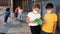 Group of preteen children in face masks resting outdoors in schoolyard during break in lessons. Back school concept