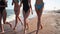 Group of pretty girls friends running by the sea on sandy tropical beach in swimsuits. Interracial women in bikini have