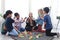 Group of primary school children study and play together in classroom with teacher, diverse students sit on floor while do