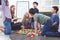 Group of primary school children study and play together in classroom with teacher, diverse students sit on floor while do