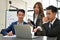 Group of professional Asian businesspeople focusing on looking at laptop screen