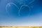 A group of professional pilots of aircraft of fighters on a sunny clear day shows tricks in the blue sky, drawing a romantic heart