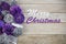 Group of purple and silver Christmas decoration on a wooden background with text in English `Merry Christmas`