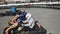 A group of racers on karts are approaching the finish line in an active battle for first place in the championship, sreet, rent. E