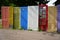 Group of random colorful doors being used as decorative yard fence.