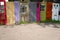 Group of random colorful doors being used as decorative yard fence.
