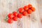 Group of red cherry tomatoes, bunch, vine, close up, wood backg