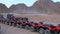 Group of Red Quad Bikes stand in a parking lot in desert on backdrop of Mountains. Driving ATVs