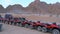 Group of Red Quad Bikes stand in a parking lot in desert on backdrop of Mountains. Driving ATVs