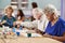 Group Of Retired Seniors Attending Art Class In Community Centre With Teacher