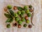 Group of ripe macamadia nuts in green and brown shell and leaves of macadamia tree