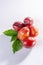 Group of ripe oval Victoria plums from England on white background with leaves