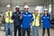 Group of robotic engineers wear helmets safety standing and raising fist work success at factory workshop