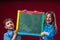Group of school children, boy and girl, hold empty blackboard for copying space