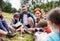 Group of school children with teacher and windmill model on field trip in nature.