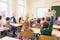 Group of school kids raising hands in classroom