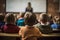 group of school kids seated in a classroom, listening to teacher view from the back