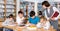 Group of school kids studying in school library with friendly female teacher