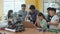 Group of schoolchildren with teacher interacting using gadgets laptops for programming at robotics engineering class