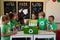 Group of schoolchildren wearing green t shirts with a white recycling logo on them standing around a