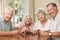 Group Of Senior Couples Enjoying Game Of Dominoes At Home