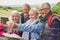 Group Of Senior Friends Hiking In Countryside Standing By Gate  And Taking Selfie On Mobile Phone