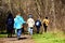 a group of senior women walking along forest trail with walking poles. Spring forest scene. Colorful winter attire