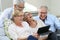 Group of seniors laughing and using tablet